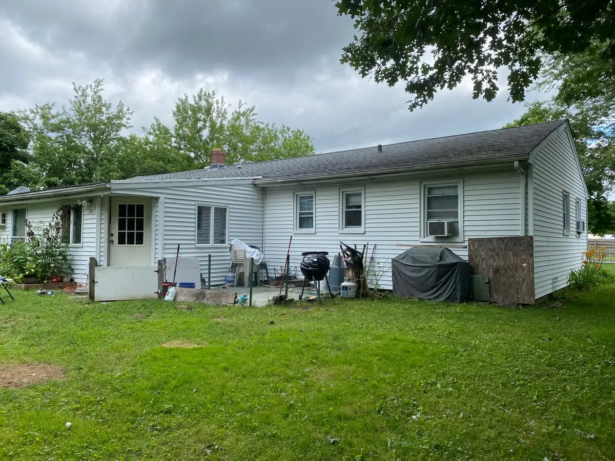 Selling a house during a divorce in Patchogue: back of a ranch with furniture and belongings stacked on the patio