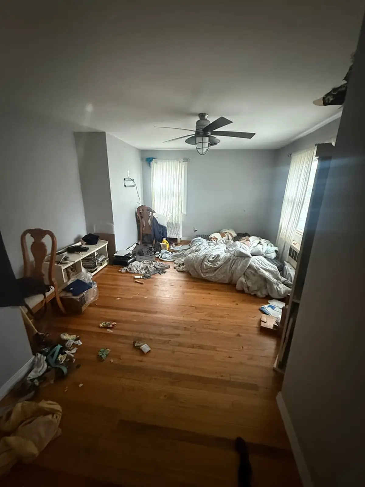 Selling a house for a job relocation in Patchogue: bedroom with clothes and belongings heaped on the floor