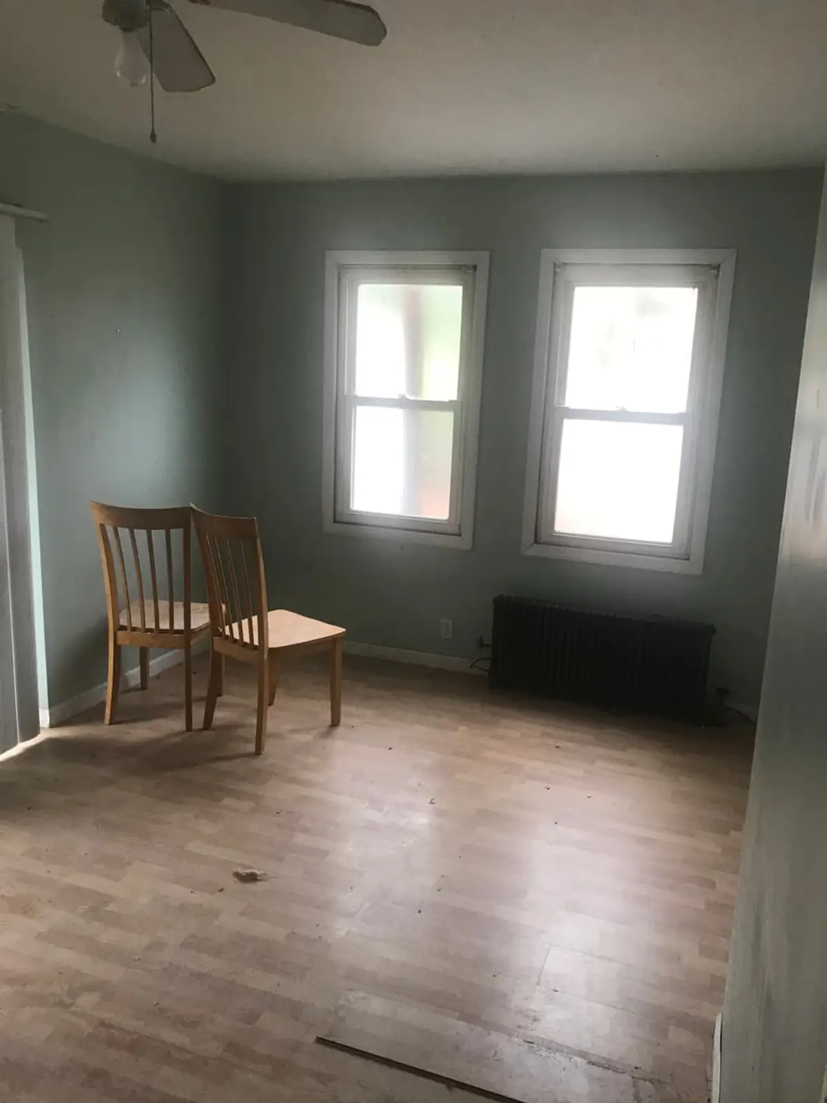 Selling a house in a flood zone in Patchogue: empty bedroom with green walls and a single wooden chair