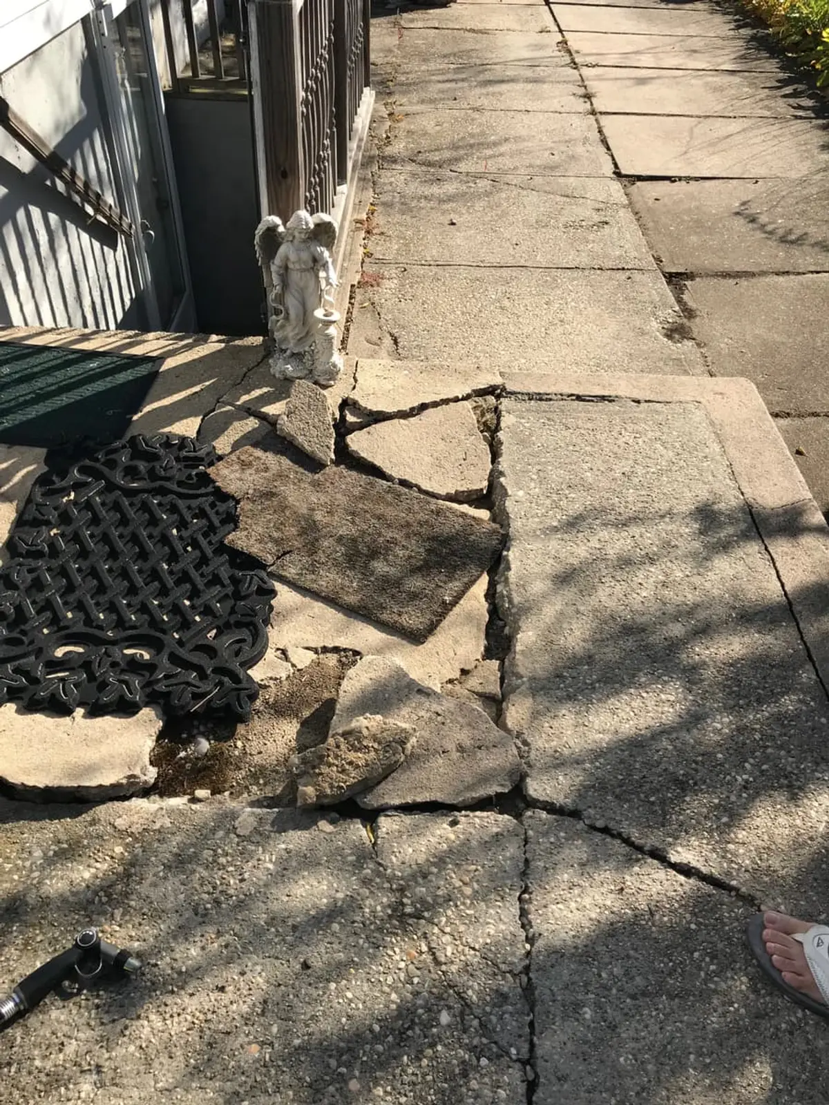 Selling a fire-damaged house in Patchogue: front walk with broken, heaved concrete slabs