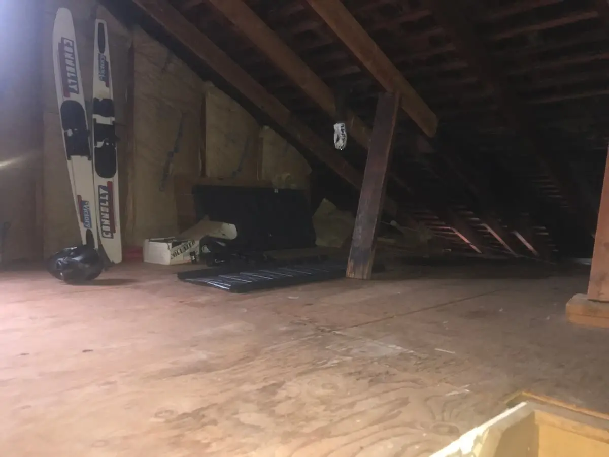 Selling a vacant house in Patchogue: open attic with bare rafters and a plywood floor