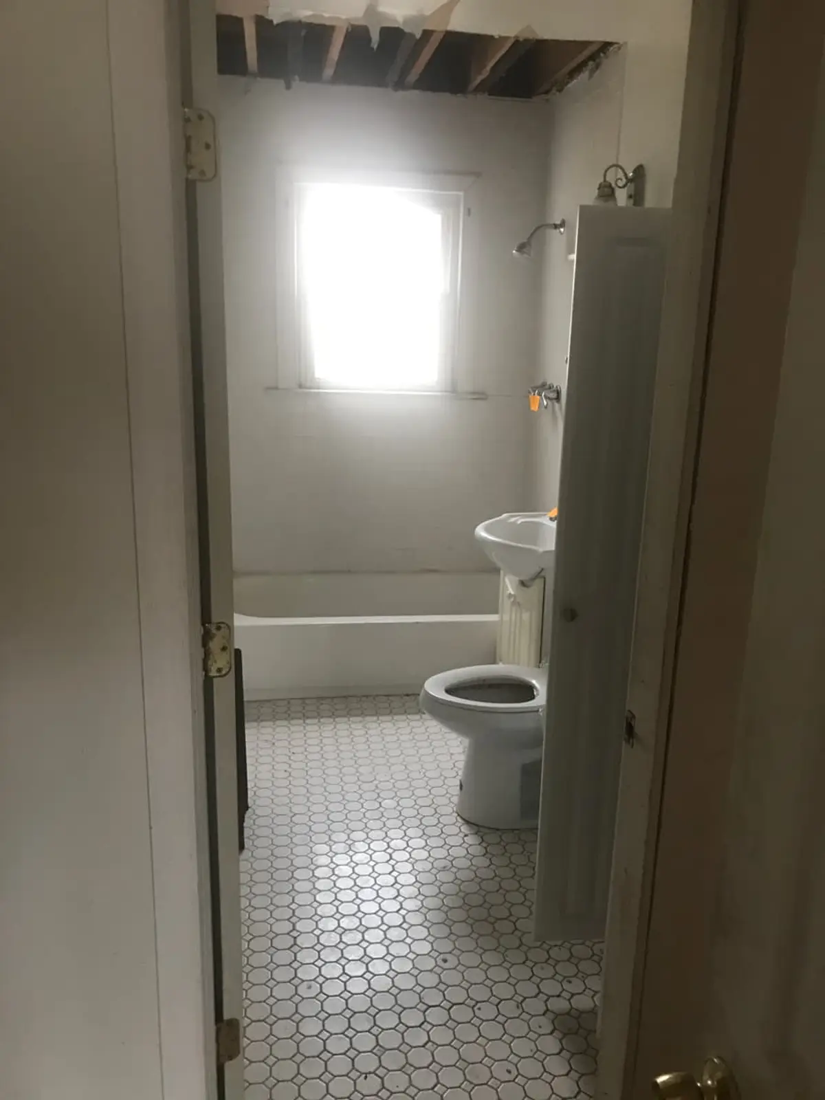 Selling a house with a reverse mortgage in Patchogue: small bathroom with hex tile and an open ceiling