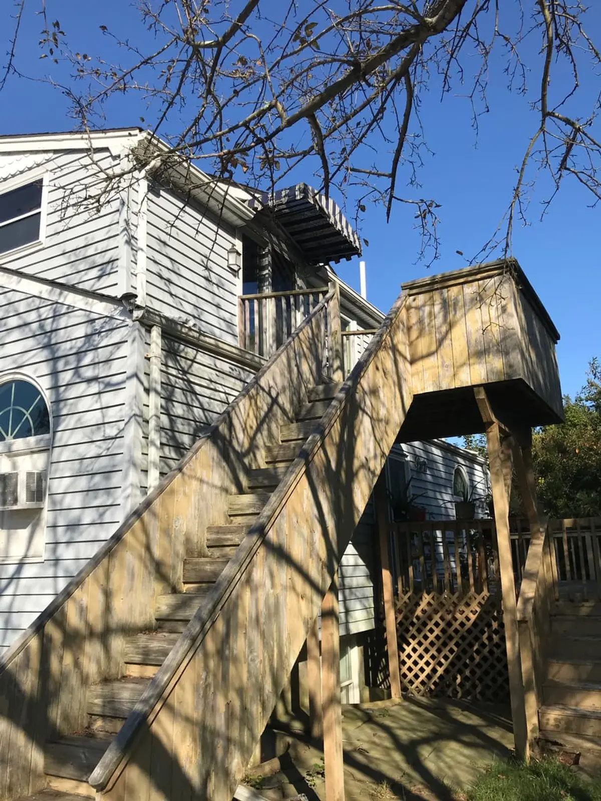 Selling a house as-is in Patchogue: weathered wooden stair up to a second-floor deck