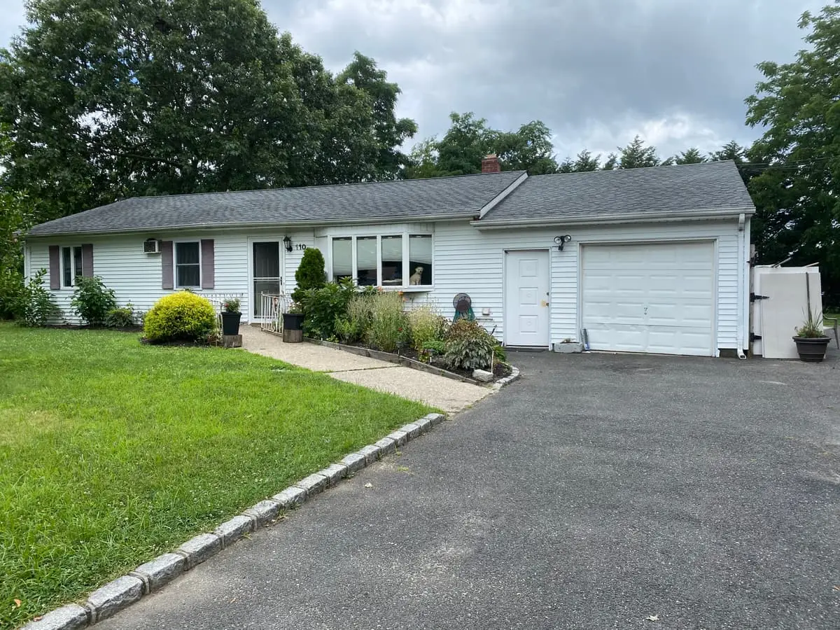 Selling a house in pre-foreclosure in Patchogue: white ranch with a two-car garage and a long driveway